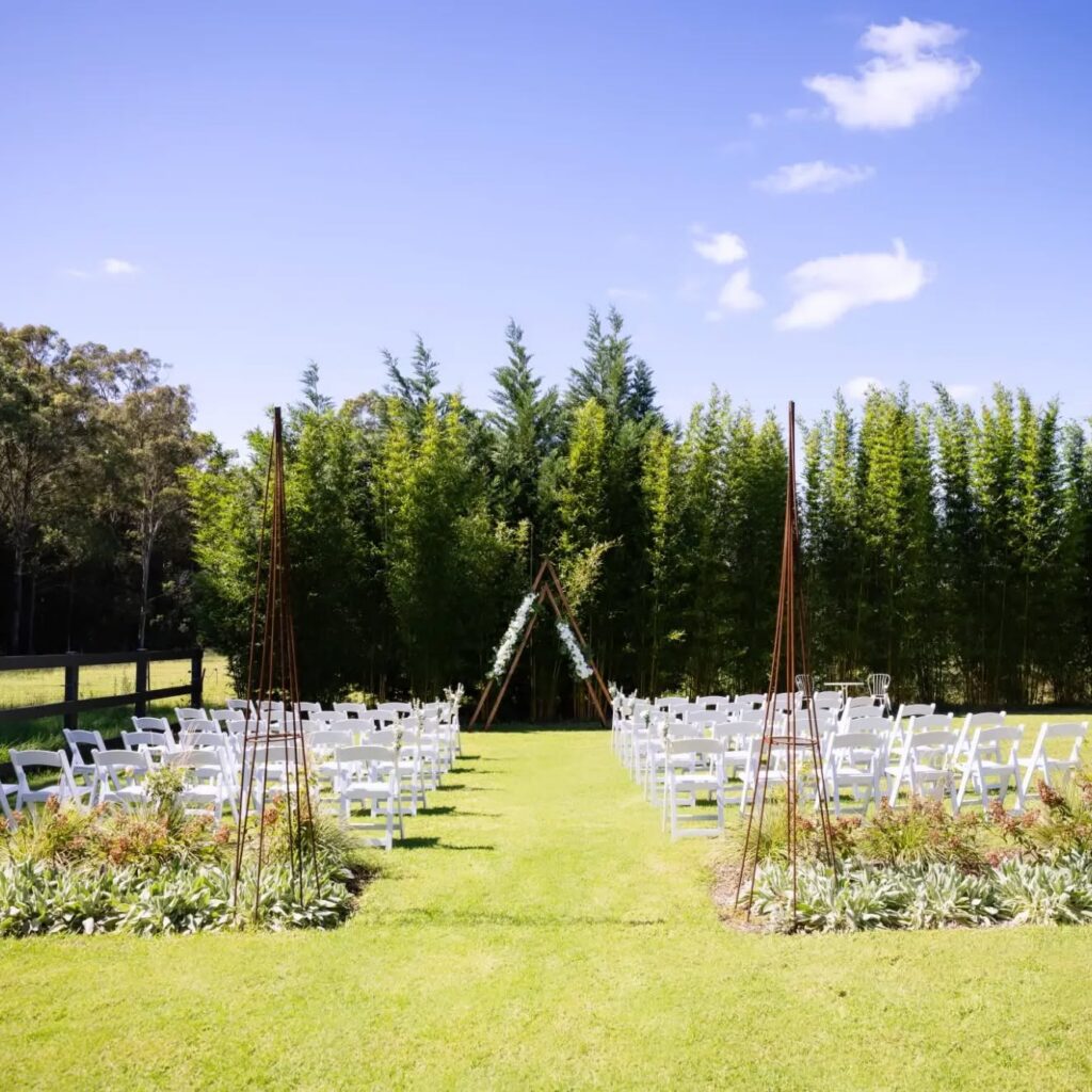 Rows of white Americana ceremony chairs set up in a field for a wedding