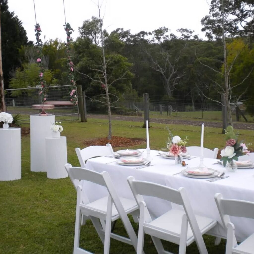 Long table set with white linen, chairs and plinths