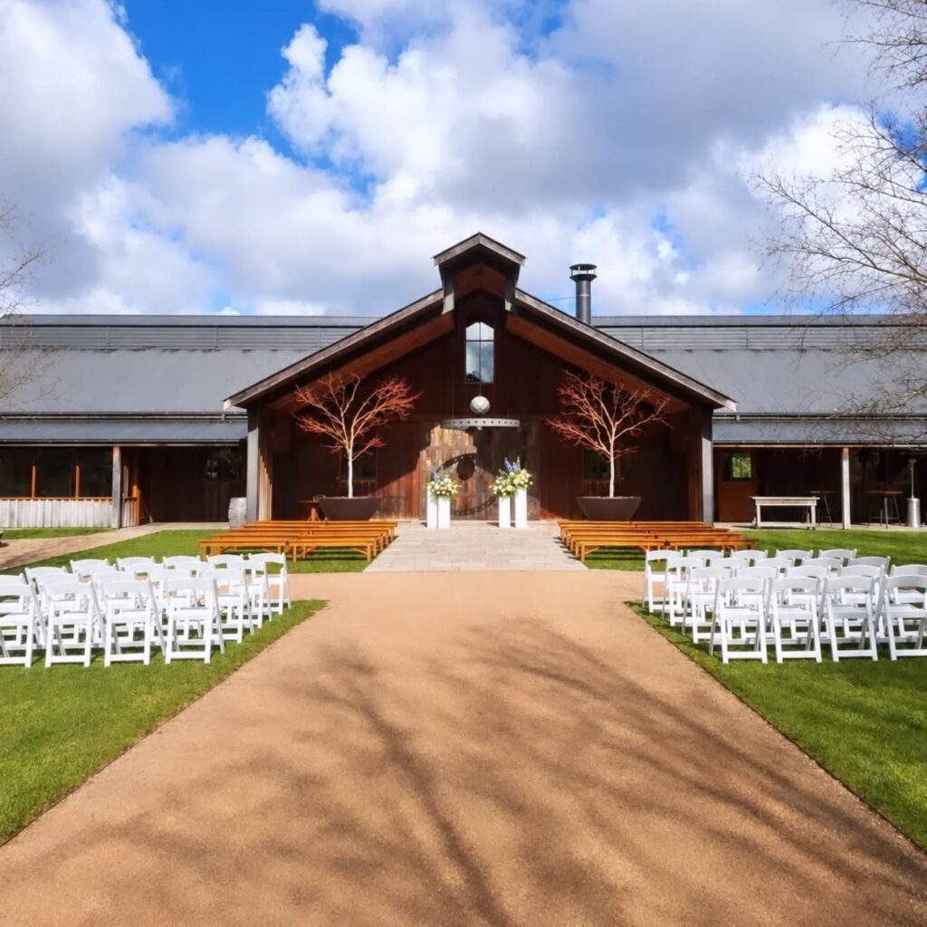 Wedding ceremony aisle lined with white folding chairs at a barn venue