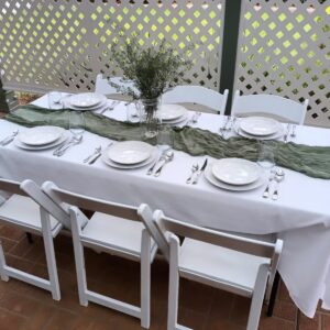 Trestle table dressed in white linen with a green runner and place settings